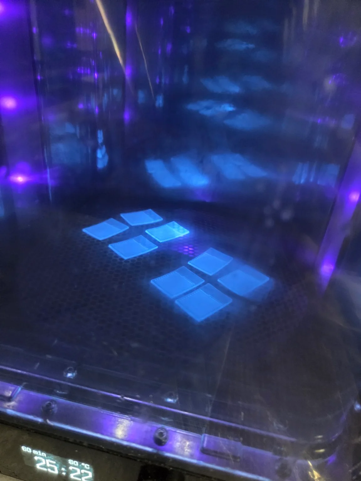 Microfluidic prototype pieces inside blue-lit fabrication equipment